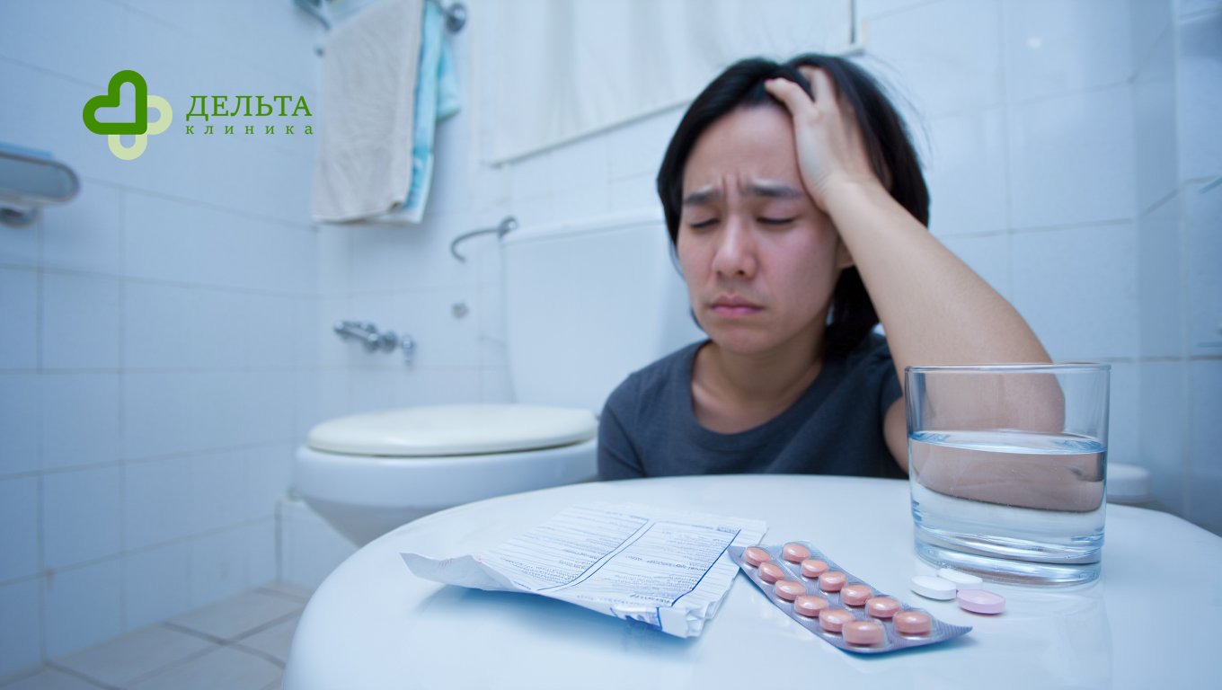 Человек сидит возле унитаза, рядом таблетки